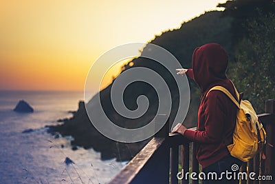 Hipster hiker tourist with backpack looking of amazing seascape sunset on background blue sea, girl enjoying ocean horizon, panora Stock Photo