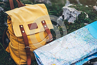 Hipster hiker tourist yellow backpack closeup and navigation map europe on background green grass nature, blurred panoramic landsc Stock Photo