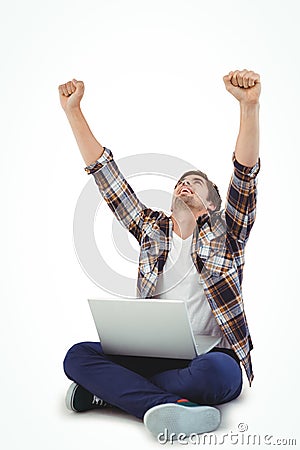 Hipster with laptop on lap cheering with arms raised Stock Photo