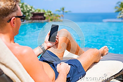Man holding mobile phone while relaxing by the pool. Stock Photo