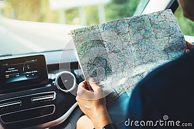 Hipster man looking and point finger on location navigation map in car, tourist traveler driving and hold in male hands europe car Stock Photo