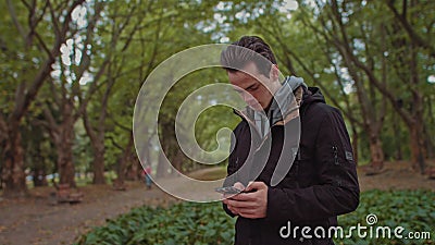 Hipster Man sending voice messages with mobile phone at park, teenager student use audio message search on grass in park Stock Photo