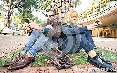 Hipster millennial couple in disinterest moment with smartphone - Apathy concept about sadness and isolation using mobile phone Stock Photo