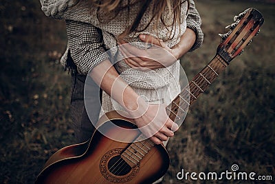 Hipster musician couple hugging in field, handsome man embracing Stock Photo