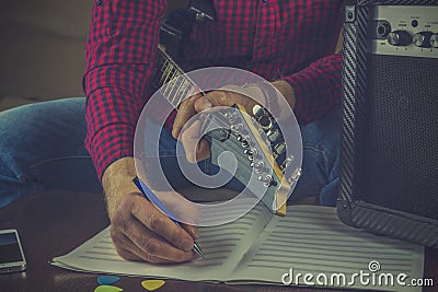 Hipster musician sits on the couch with an electric guitar and r Stock Photo