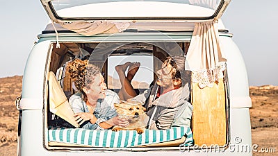 Hipster people with cute dog traveling together on vintage minivan - Wanderlust and life inspiration concept with hippie couple Stock Photo