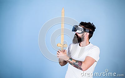 Hipster on serious face enjoy play game in virtual reality. Gamer concept. Man with beard in VR glasses, light blue Stock Photo