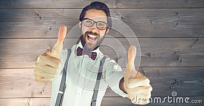 Hipster showing thumbs up against wall Stock Photo