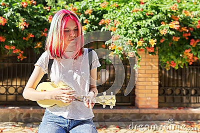 Hipster teenager playing ukulele sitting outdoors Stock Photo