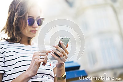 Hipster texting message on smartphone or technology, mockup of blank screen. Girl using cellphone on building castle background Stock Photo