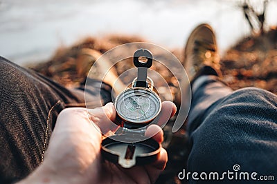 Hipster traveler hold vintage compass in hand on background of him legs in hiking boots Stock Photo