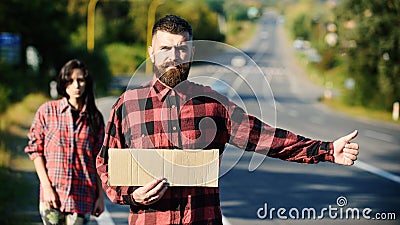 Hipster try to stop car with cardboard sign and thumb Stock Photo