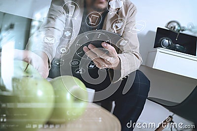 hipster using smart phone for mobile payments online business,sitting on sofa in living room and holding green apple in wooden t Stock Photo