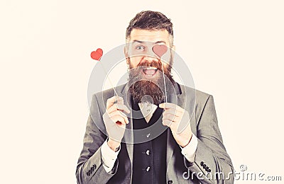 Hipster wears smart suit and bow-tie. Mature man with long beard and cheerful face. Bearded man smiles and holds red Stock Photo