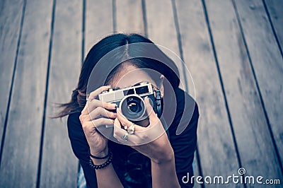 Hipster woman taking photos with retro film camera on wooden floorof city park,beautiful girl photographed in the old camera Stock Photo