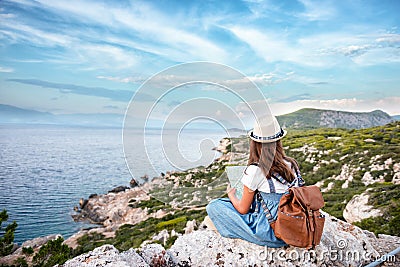 Hipster young girl with bright backpack enjoying panoramic mountain sea, using map and looking distance. Tourist traveler on Stock Photo