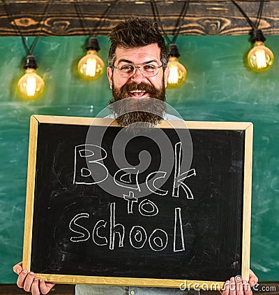 Hiring teachers concept. Man with beard and mustache on happy face welcomes colleagues, chalkboard on background Stock Photo