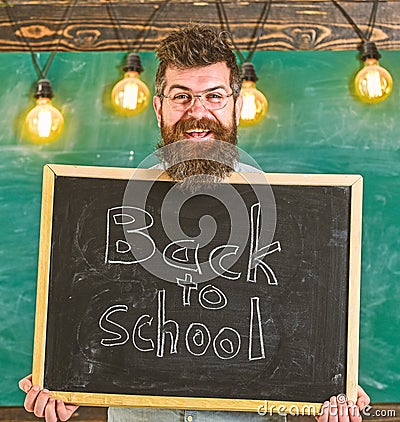 Hiring teachers concept. Man with beard and mustache on happy face welcomes colleagues, chalkboard on background Stock Photo