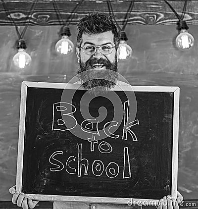 Hiring teachers concept. Man with beard and mustache on happy face welcomes colleagues, chalkboard on background Stock Photo