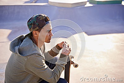 His favourite place to think. A young skater sitting down at a skate park. Stock Photo