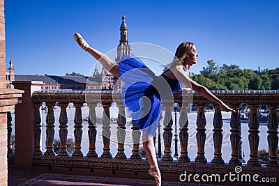 Hispanic adult female classical ballet dancer in blue tutu doing figures on the terrace of a plaza next to a beautiful tiled Stock Photo