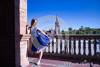 Hispanic adult female classical ballet dancer in blue tutu doing figures on the terrace of a plaza next to a beautiful tiled Stock Photo