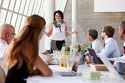 Hispanic Businesswoman Leading Meeting At Boardroom Table Stock Photo