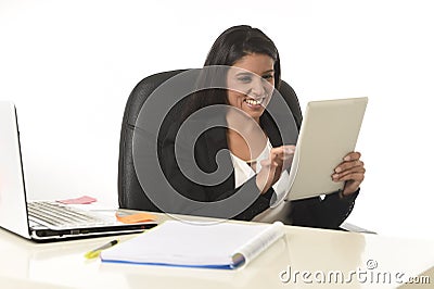 Hispanic businesswoman sitting at office computer desk smiling happy using digital tablet Stock Photo