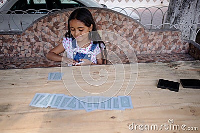 hispanic child girl playing making magic tricks with cards Stock Photo