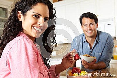 Hispanic couple eating cereal and fruit in kitchen Stock Photo