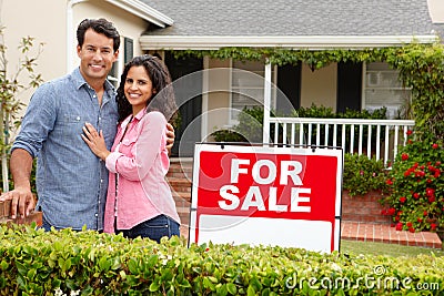 Hispanic couple satnding with a sign outside house Stock Photo