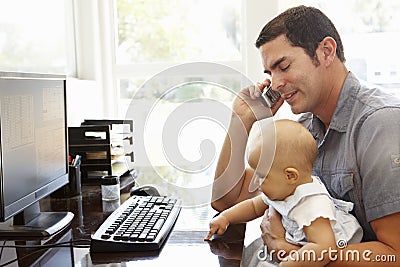 Hispanic father with baby working in home office Stock Photo