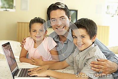 Hispanic Father And Children Using Computer At Home Stock Photo