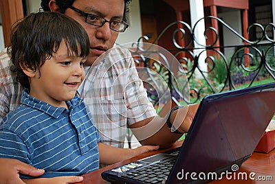 Hispanic father and son on laptop Stock Photo