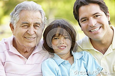 Hispanic Grandfather, Father And Son Relaxing In Park Stock Photo