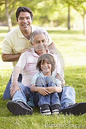 Hispanic Grandfather, Father And Son Relaxing In Park Stock Photo