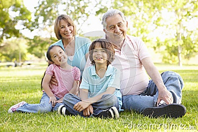 Hispanic Grandmother And Grandfather Relaxing With Grandchildren In Park Stock Photo