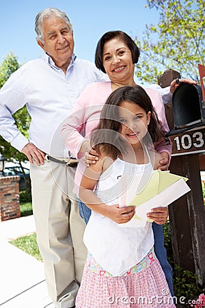 Hispanic Grandparents And Granddaughter Checking Mailbox Stock Photo