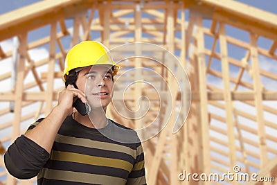 Hispanic Male Contractor on Phone in Front of House Framing Stock Photo