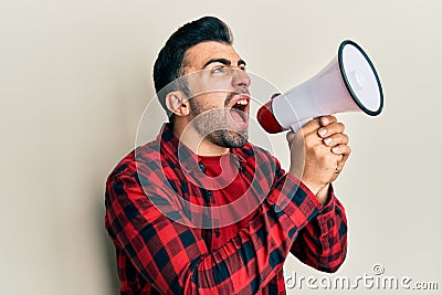 Hispanic man with beard screaming with megaphone Stock Photo