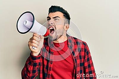 Hispanic man with beard screaming with megaphone Stock Photo