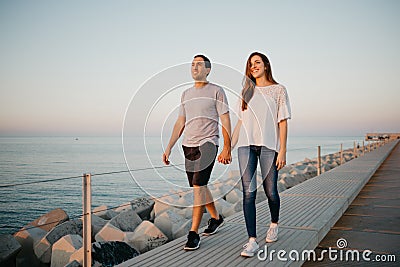 A Hispanic man and his girlfriend are strolling on a breakwater in Spain Stock Photo