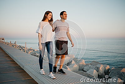 A Hispanic man and his girlfriend are strolling on a breakwater in Spain Stock Photo