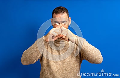 Hispanic man in his 40s crossing his fingers in stop and protest against the total oppression of the elites towards the Stock Photo
