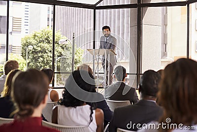 Hispanic man presenting business seminar leaning on lectern Stock Photo