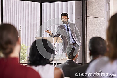 Hispanic man presenting business seminar leaning on lectern Stock Photo