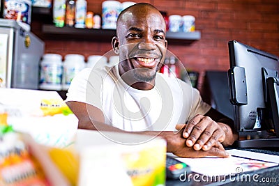 hispanic man selling professional plastic jar with sport nutrition in reception of gym Stock Photo