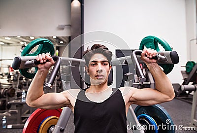 Hispanic man training in gym, doing machine shoulder press. Stock Photo