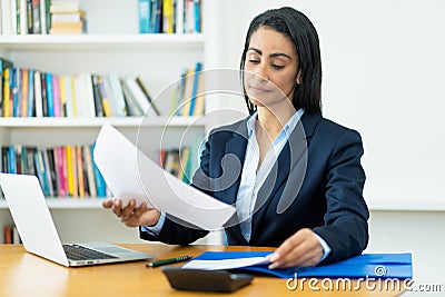 Hispanic mature businesswoman working with documents at desk Stock Photo