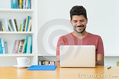 Hispanic mature man with beard at video call at computer Stock Photo
